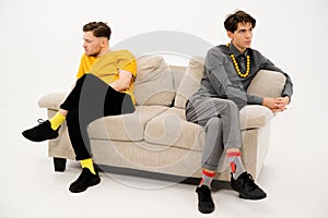 Two Friends Quarreled and Sat on Opposite Sides of the Sofa. Men are in a Quarrel and sit on the Couch at a Distance