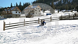 Two Friends are Rolling Huge Snowball up the Hill and the Third Girl is Running to Help Them. Happy Children are Playing