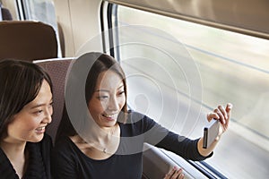 Two Friends Smiling and Taking a Picture Out the Train Window