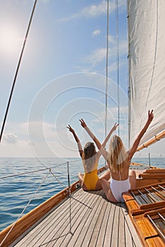 Two friends in swimsuits making peace signs celebrating on a boat cruise. Two women cheerfully celebrating making peace