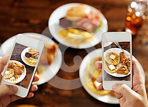 Two friends taking photo of their food with smartphones photo