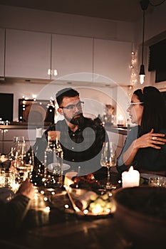 Two friends talking during a candlelit dinner party with friends