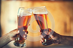 Two friends toasting with glasses of light beer at the pub