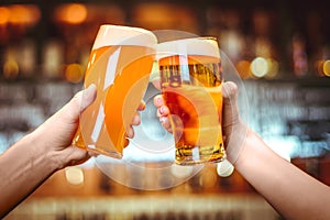 Two friends toasting with glasses of light beer at the pub. Beautiful background of the Oktoberfest. fine grain