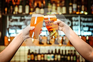 Two friends toasting with glasses of light beer at the pub. Beautiful background of the Oktoberfest. fine grain