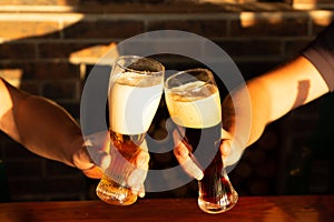 Two friends toasting with glasses of light and dark beer at the pub. Beautiful background of the Oktoberfest.