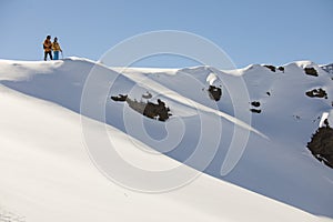 Two friends on the top of the snowy mountain about to drop in