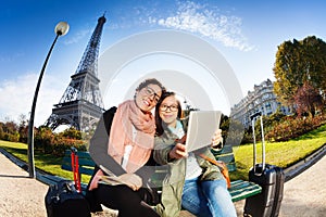 Two friends using a tablet taking selfie in Paris