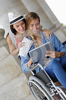 Two friends visiting foreign city one sitting in wheelchair