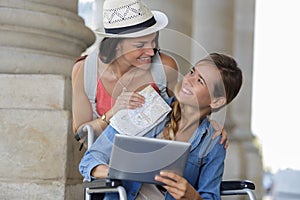 Two friends visiting foreign city one sitting in wheelchair