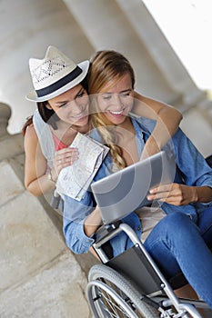 Two friends visiting foreign city one sitting in wheelchair