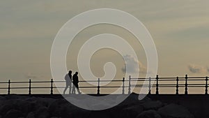 Two friends walking on the pier after dusk