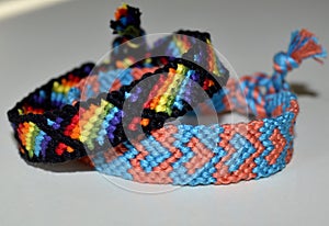 Two friendship bracelets, woven of thread, with ties and pattern of the rainbow flag, known as the gay pride flag or LGBT pride f