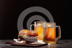 Two frosty mugs of light beer and two hamburgers