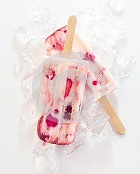 Two frozen yogurt and berry popsicles on sticks