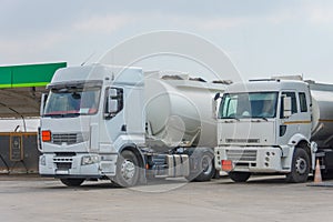 Two fuel trucks delivering fuel to the city fuel station parking