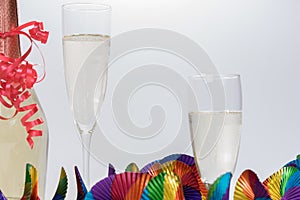 Two full champagne glasses and bottle with colorful garlands