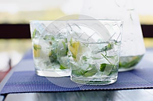 Two full glasses of fresh cool transparent water with ice, lemon and , basil leaves