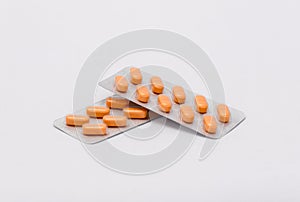 Two full sealed packages with orange rectangular pills lie on a white background