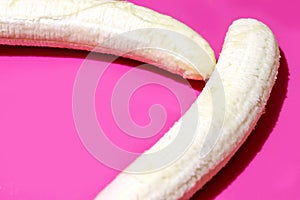 Two fully peeled bananas on a bright pink background top view close-up. Flat lay with copy space for text