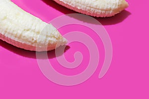 Two fully peeled bananas on a pink background top view close-up. Flat lay with copy space for text