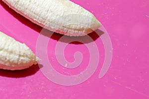 Two fully peeled bananas on a pink background top view close-up. Flat lay with copy space for text