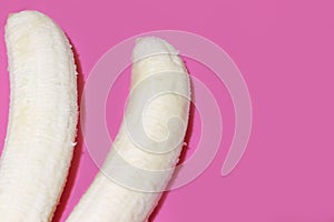 Two fully peeled bananas on a pink background top view. Flat lay with copy space for text