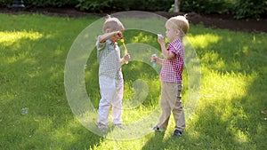 Two fun little kids are playing with soap bubbles in the Park at sunset.