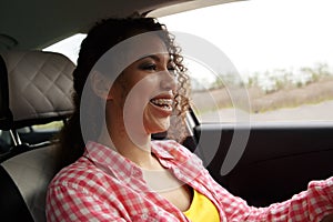 Two fun young women in sunglasses driving in a car in town laughing and smiling as they socialise together, view through