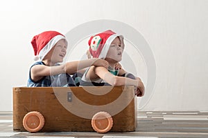 Two funny boys in a Santa Claus hat are playing with horses drawn on cardboard. The guys have fun at home. Christmas holiday conce