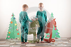 Two funny boys in a Santa Claus hat are playing with horses drawn on cardboard. The guys have fun at home. Christmas holiday conce