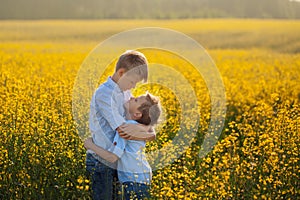 Two funny brother hugging with each other while walk in yellow field. Friendship concept.