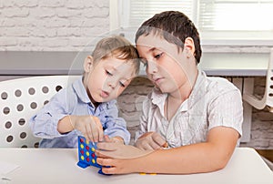 Two funny brothers are playing a board game together on desk at home