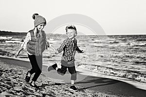 Two funny Caucasian children kids friends playing running on ocean sea beach on sunset