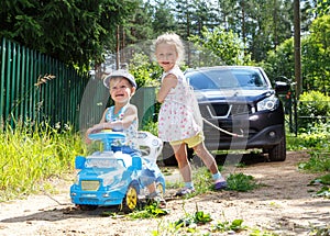 Two funny children trying to tow real car by rope