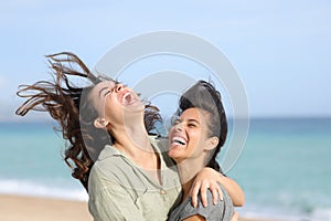Two funny friends laughing hilariously on the beach photo