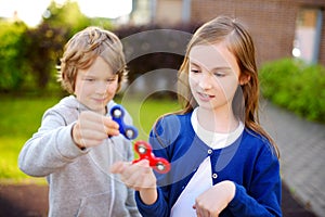 Two funny friends playing with fidget spinners on the playground. Popular stress-relieving toy for school kids and adults.