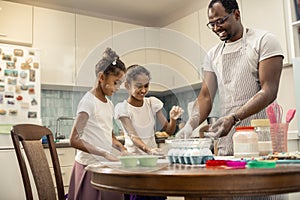 Two funny girls cooking pie with their loving helpful father