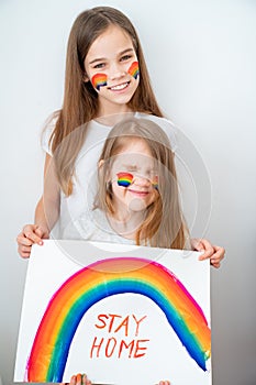 Two funny girls drew rainbow and poster stay home. photo