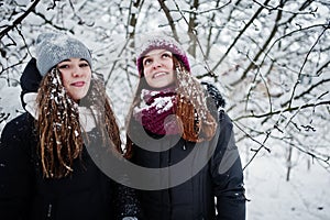 Two funny girls friends having fun at winter snowy day near snow covered trees