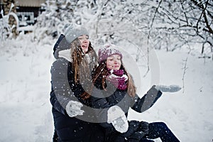 Two funny girls friends having fun at winter snowy day near snow covered trees