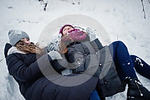 Two funny girls friends having fun at winter snowy day near snow covered trees