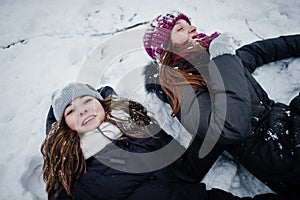 Two funny girls friends having fun at winter snowy day near snow covered trees