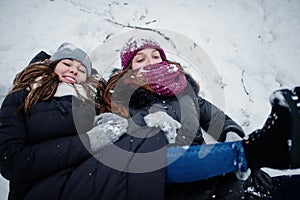 Two funny girls friends having fun at winter snowy day near snow covered trees