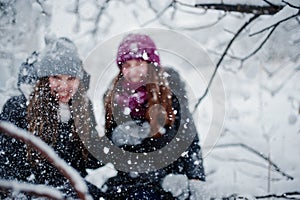 Two funny girls friends having fun at winter snowy day near snow covered trees