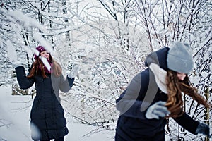 Two funny girls friends having fun at winter snowy day near snow covered trees