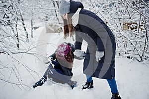 Two funny girls friends having fun at winter snowy day near snow covered trees