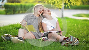 Two funny girls are playing with books. They are smiling and having a lot of fun. The Weather is sunny.