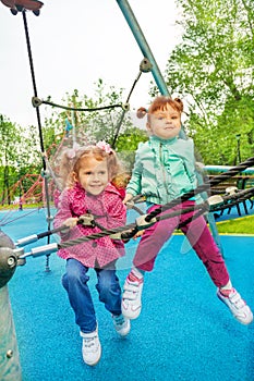 Two funny girls together on grid of playground