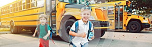 Two funny happy Caucasian boys students kids running near yellow bus on 1 September day. Education back to school. Children ready